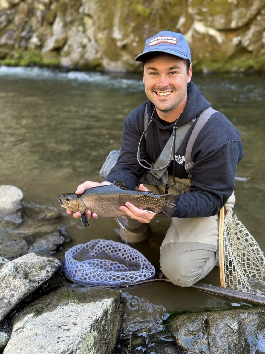 Angler holding a wild native brook trout above a Blue Ridge stream