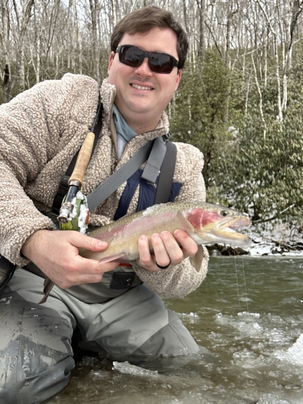 Angler holding a large rainbow trout on a snowy winter day